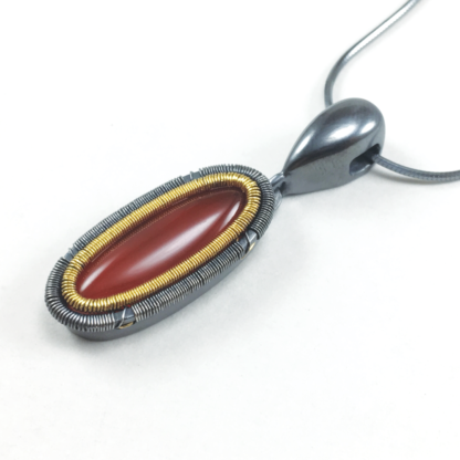 Angleshot of patinated Jack Boglioli pendant from the Simply Unique Collection with carnelian and 24k gold