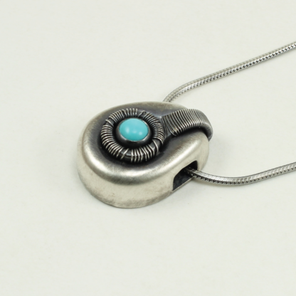 Angle shot of small Jack Boglioli pendant from the Boldly Unique Collection with slight patina and turquoise