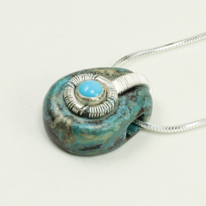 Angle shot of small Jack Boglioli pendant from the Boldly Unique Collection with green patina and turquoise