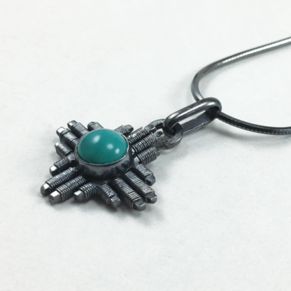Angle shot small Jack Boglioli Zia pendant from the New Mexico Collection with turquoise and patina