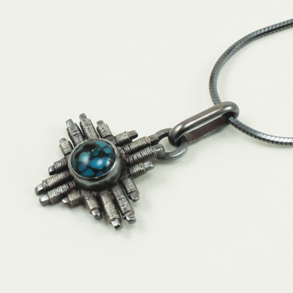 Angle shot of small Jack Boglioli Zia pendant from the New Mexico Collection with turquoise and patina