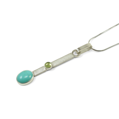 Angle shot of Jack Boglioli bound silver bar pendant with turquoise and peridot